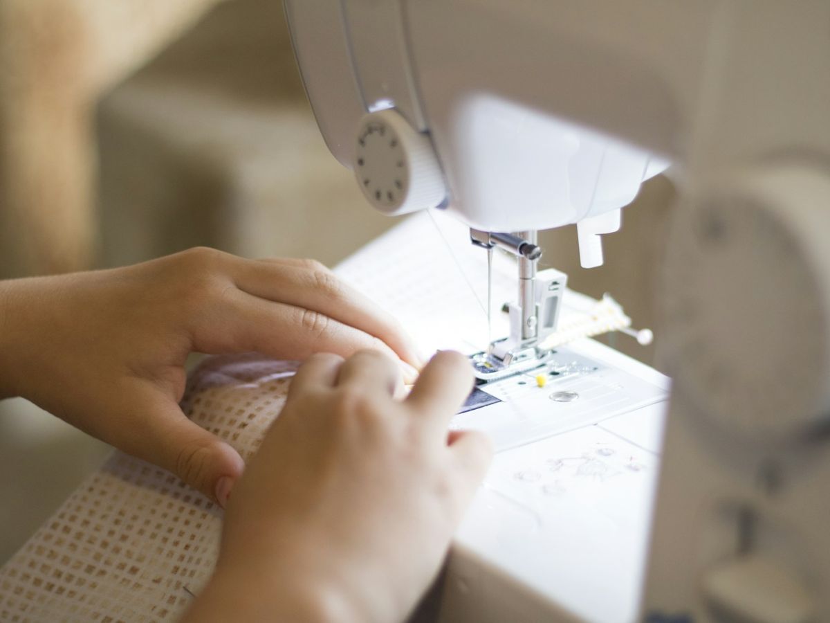 Costurera ajustando una prenda en la máquina de coser